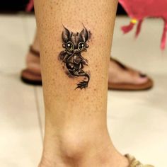 a cat tattoo on the leg of a woman's foot, which is decorated with black ink