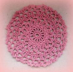 a pink crocheted doily on a white surface