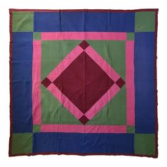 a colorful quilt with pink, green and blue squares on it's edges is displayed