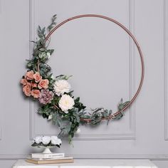 a round metal frame with flowers and greenery around it on top of a table