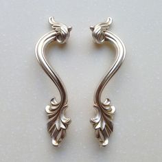 two silver colored metal handles on a white surface