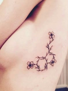 a woman's chest with a tattoo on it that has flowers growing out of it