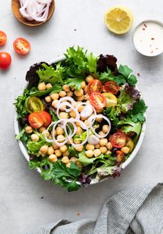 a salad with chickpeas, tomatoes, onions and lettuce in a bowl