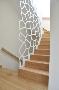 a white staircase with wooden handrails next to a light wood flooring area