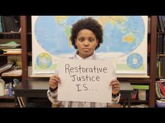 a girl holding up a sign that says restorative justice is