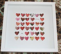 a white frame filled with lots of heart shaped paper cut outs on top of a table