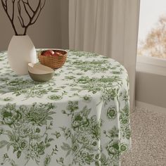 a table topped with a bowl of fruit next to a vase