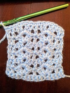 a crochet square with a green knitting needle next to it