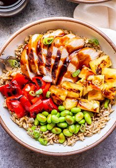 a bowl filled with rice, meat and veggies on top of a table