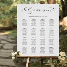 a sign that says the guest list on it with flowers in front of trees and rocks