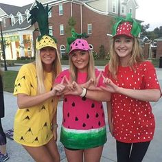 three women dressed in fruit costumes posing for the camera with their hands up and smiling