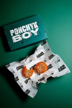 two donuts sitting on top of a wrapper next to a box