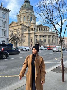 a woman standing on the sidewalk in front of a large building with a domed dome