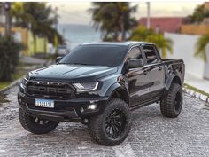 a black truck parked on top of a cobblestone road