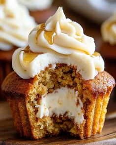 cupcakes with white frosting and caramel topping on a wooden cutting board