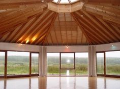 an empty room with large windows and wooden ceiling