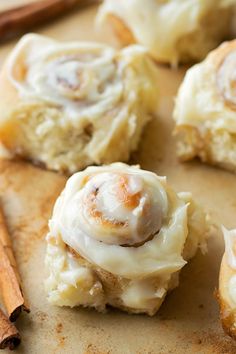 cinnamon rolls with icing sitting on top of a cutting board