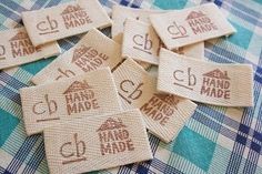 six hand made labels are laid out on a plaid tablecloth, with the letters and numbers printed onto them