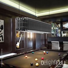 a pool table in a room with several balls on it and a guitar hanging from the ceiling