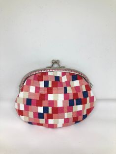 a red, white and blue purse sitting on top of a white table next to a wall