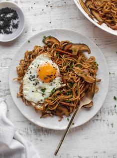 a plate of noodles with an egg on top