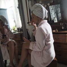 a woman sitting in front of a mirror brushing her teeth