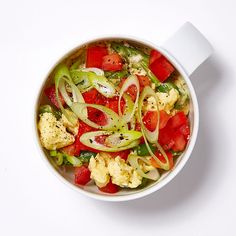 a white bowl filled with vegetables on top of a table