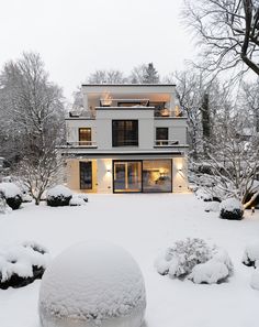 a large white house covered in snow next to some trees and bushes with lots of snow on the ground