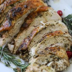 sliced pork with herbs and cranberries on a white plate