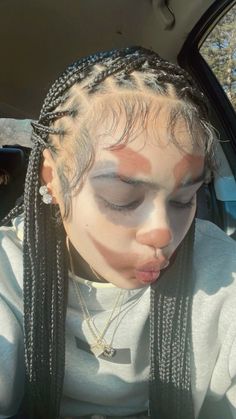 a woman with braids sticking her tongue out in the back seat of a car