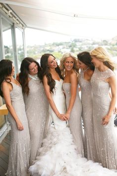 a group of women standing next to each other in front of a glass wall wearing dresses