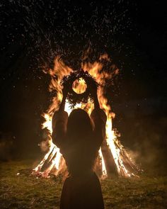 a person standing in front of a fire with their hands on top of the fire