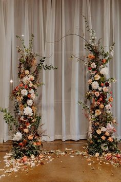 two tall floral arrangements are set up on the floor