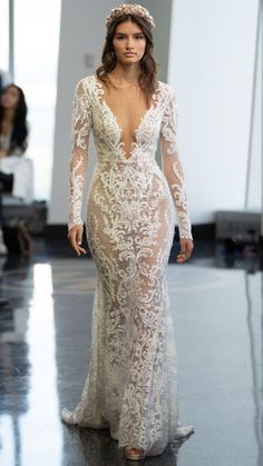 a model walks down the runway in a white gown with long sleeves and an open back