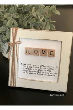 a wooden scrabble frame with the words home on it and a potted plant