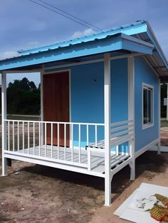 a small blue and white house sitting on top of a dirt field