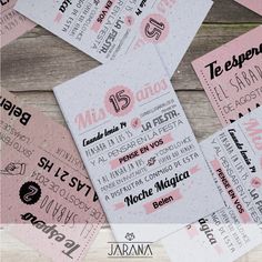 some pink and white tickets are on a wooden table with the names of different bands