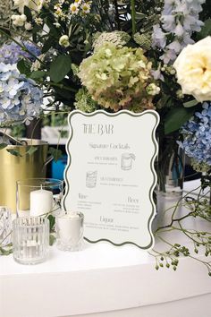 flowers and candles are sitting on a table with a sign that says the bar in front of them