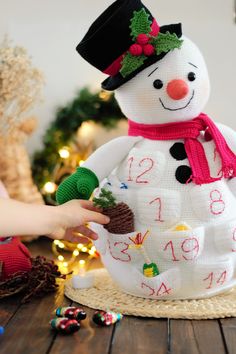 a snowman made out of knitted material on top of a wooden table next to christmas decorations