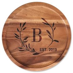 a personalized cutting board with an olive branch and the initials b, est, 2019 on it