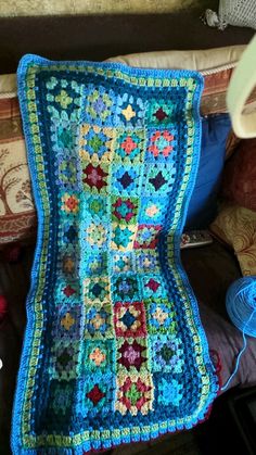 a crocheted granny blanket sitting on top of a couch