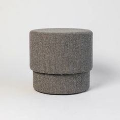 a grey ottoman sitting on top of a white floor