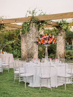 an outdoor wedding setup with white linens and floral centerpieces on the tables