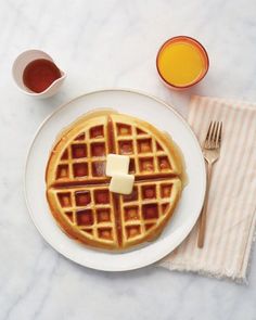 a white plate topped with waffles covered in butter next to orange slices and syrup