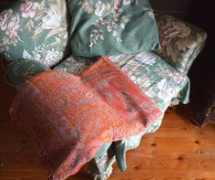 a chair covered in pillows and blankets on top of a wooden floor