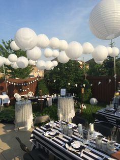 an outdoor party with white paper lanterns and black and white table cloths