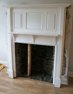 an unfinished fireplace with white paint on the mantle and wood flooring next to it