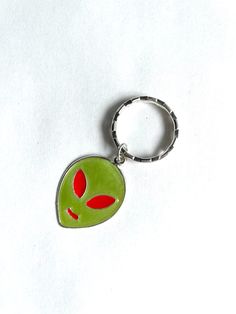 a green and red alien keychain on a white surface