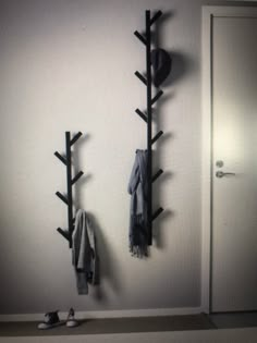 a coat rack with two coats hanging from it's sides next to a pair of shoes