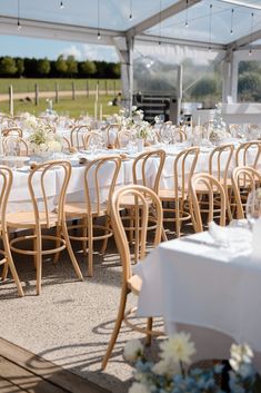 tables and chairs are set up for an outdoor wedding reception in a tented area